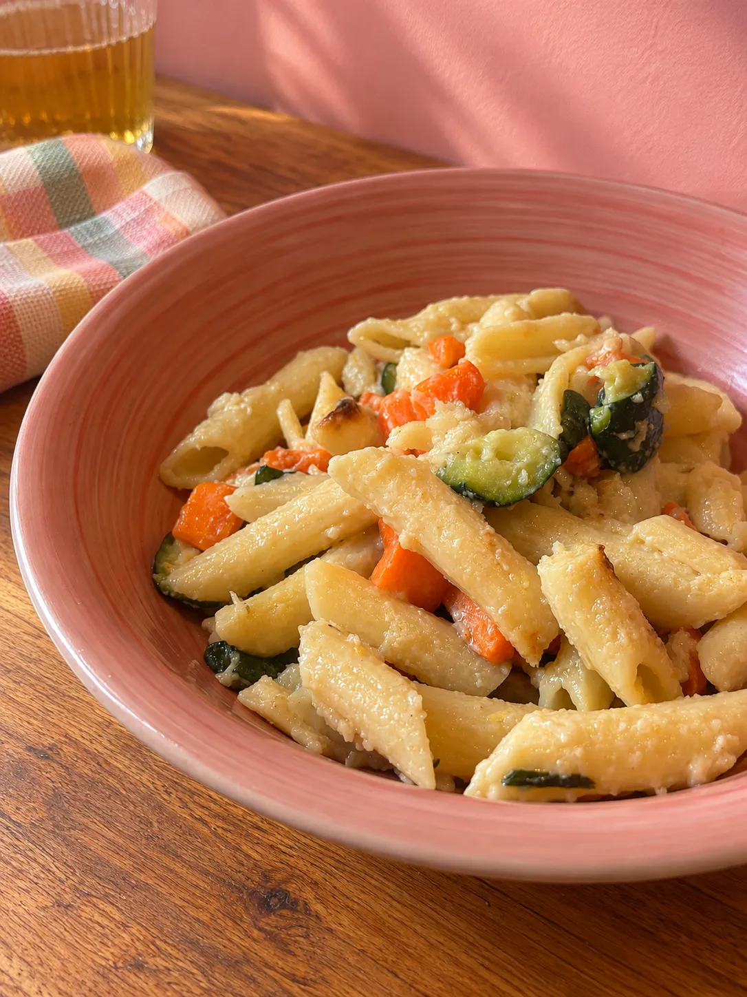 Gratin di pasta, carote e zucchine servito in un piatto fondo rosa