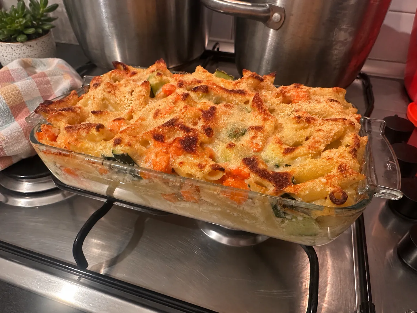 Teglia di gratin di pasta, carote e zucchine appena sfornata, con la superficie gratinata