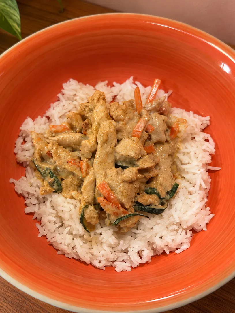 Curry soy strips with carrots and zucchini over basmati rice, on an orange plate